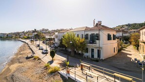A coastal building with a balcony, a paved walkway, and a view of the sea.