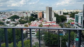 A cityscape with a prominent building in the center, surrounded by other structures and greenery.
