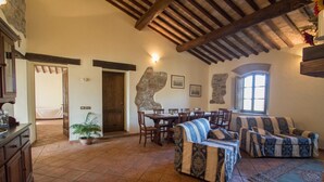 A spacious living room with a dining area, stone wall decor, and a large window.