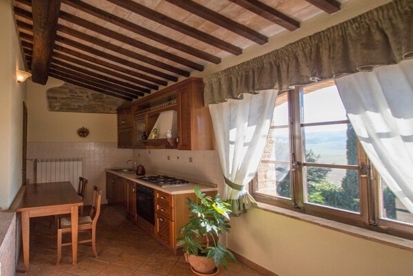 A kitchen with wooden cabinets, a stove, and a dining table with chairs.
