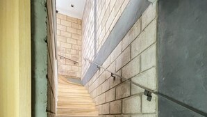 Un escalier avec des marches en bois menant vers le haut, entouré de murs en briques et en béton.