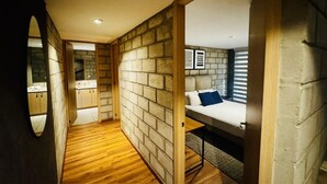 A compact room with a bunk bed, a wooden floor, and a stone wall.