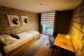 Una habitación pequeña con cama, un escritorio y ventana con persianas.