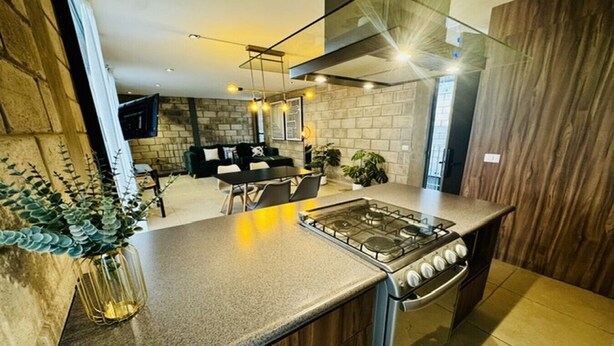 A modern kitchen with a gas stove, wooden cabinets, and a dining area with a table and chairs.
