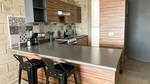 Una cocina moderna con una isla central, taburetes de bar, horno empotrado y un refrigerador de acero inoxidable.