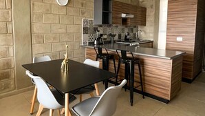 Una cocina moderna con una isla central, una mesa comedor negra con sillas y un colgante.