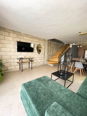 Una sala moderna con televisión, asientos, una escalera y un comedor.