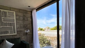 Ein Schlafzimmer mit Bett, Wandleuchte und Blick ins Freie.