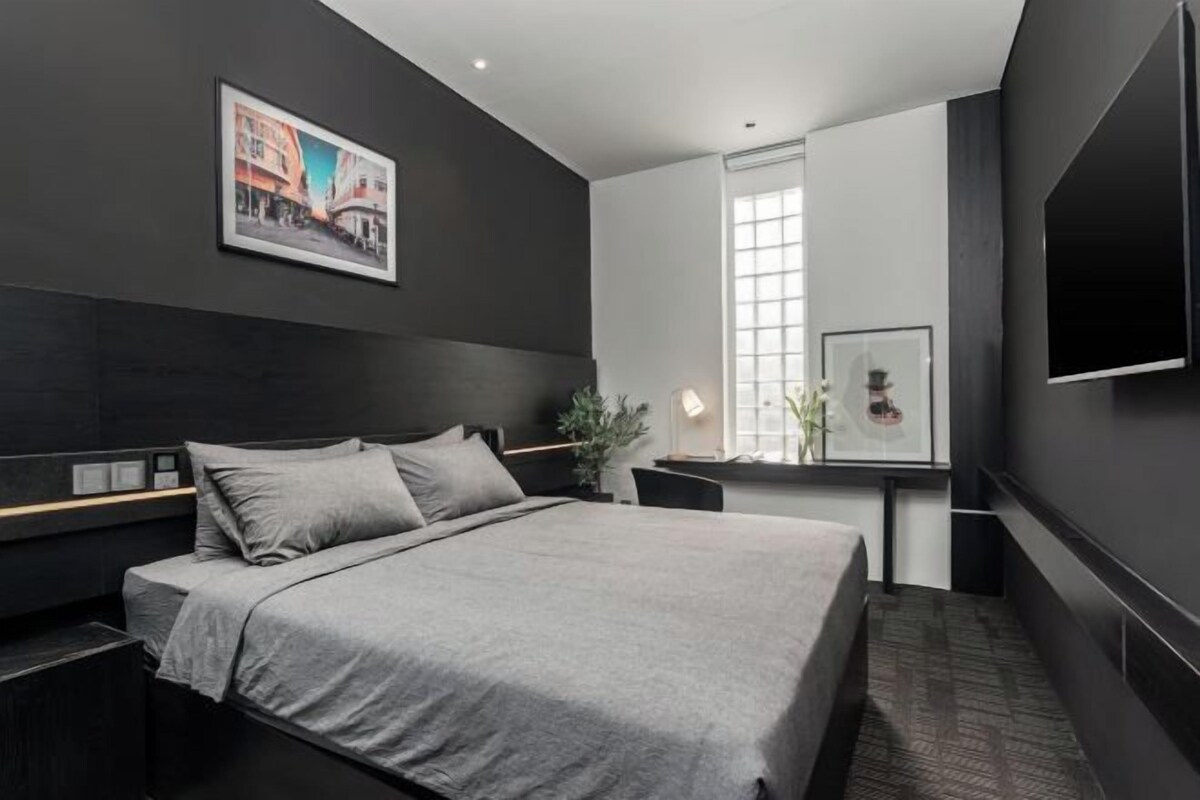 A modern hotel room with a large bed, a desk, and a television.