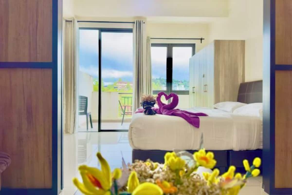 A hotel room with a bed, a view of the outside, and a balcony.