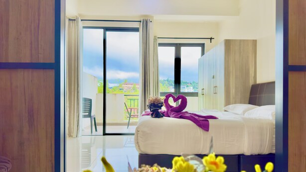 A hotel room with a bed, a balcony, and a view of the city.