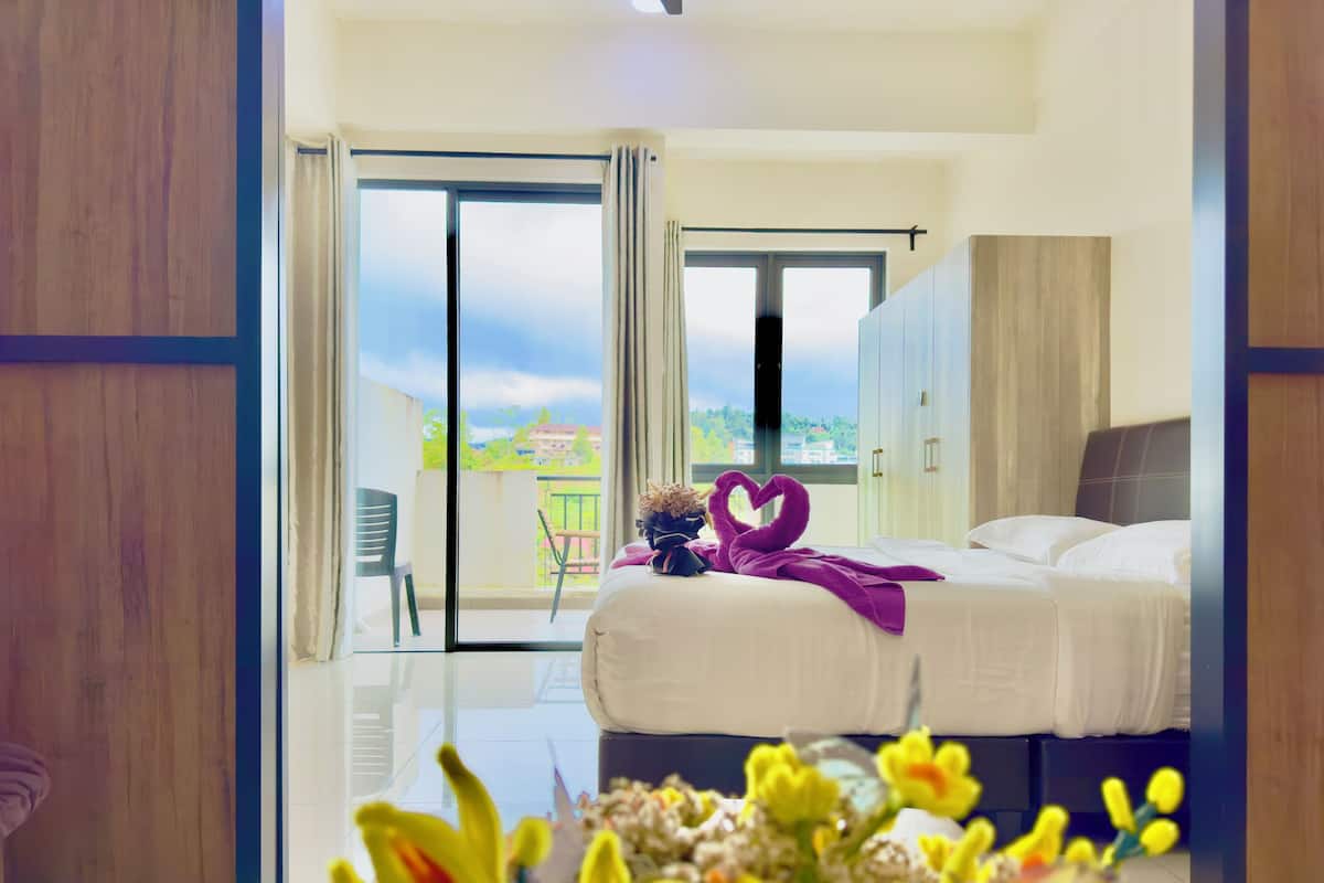 A hotel room with a bed, a balcony, and a view of the city.