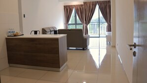 A spacious living area with a wooden reception desk, a sofa, and a balcony with curtains.