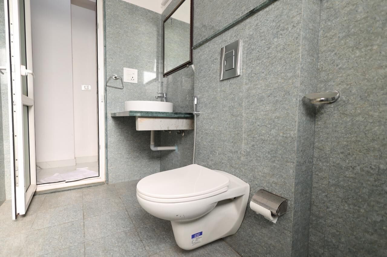 A modern bathroom with a white toilet, a glass shower enclosure, and a sink with a mirror above it.