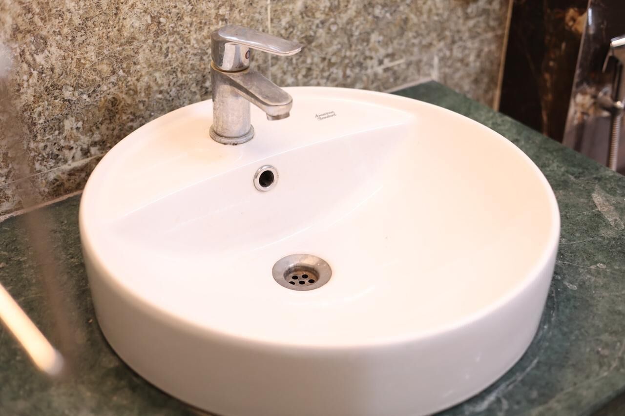 A white bathroom sink with a single faucet and a drain.