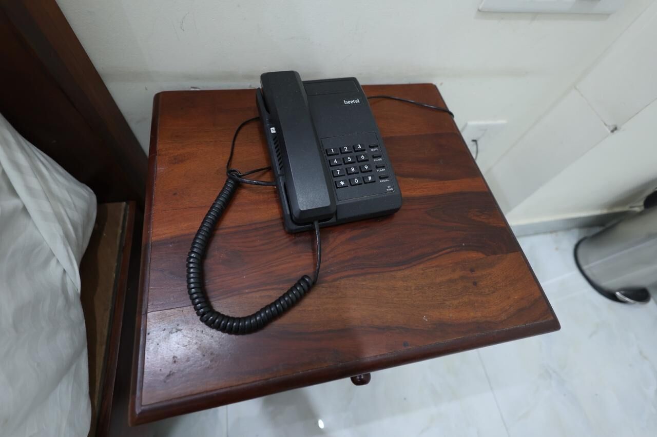 A black telephone on a wooden table.