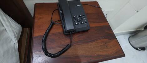 A black telephone on a wooden table.