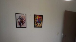 Ein Hotelzimmer mit Bett, Nachttisch und zwei gerahmten Bildern an der Wand.