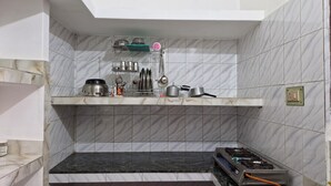 A kitchen with a marble backsplash, a built-in shelf with cookware, and a gas stove. - Private Flat with open space WiFi and AC in charming Varanasi near Assi Ghat (Varanasi)