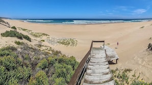 A wooden boardwalk leading to a beach with clear skies.