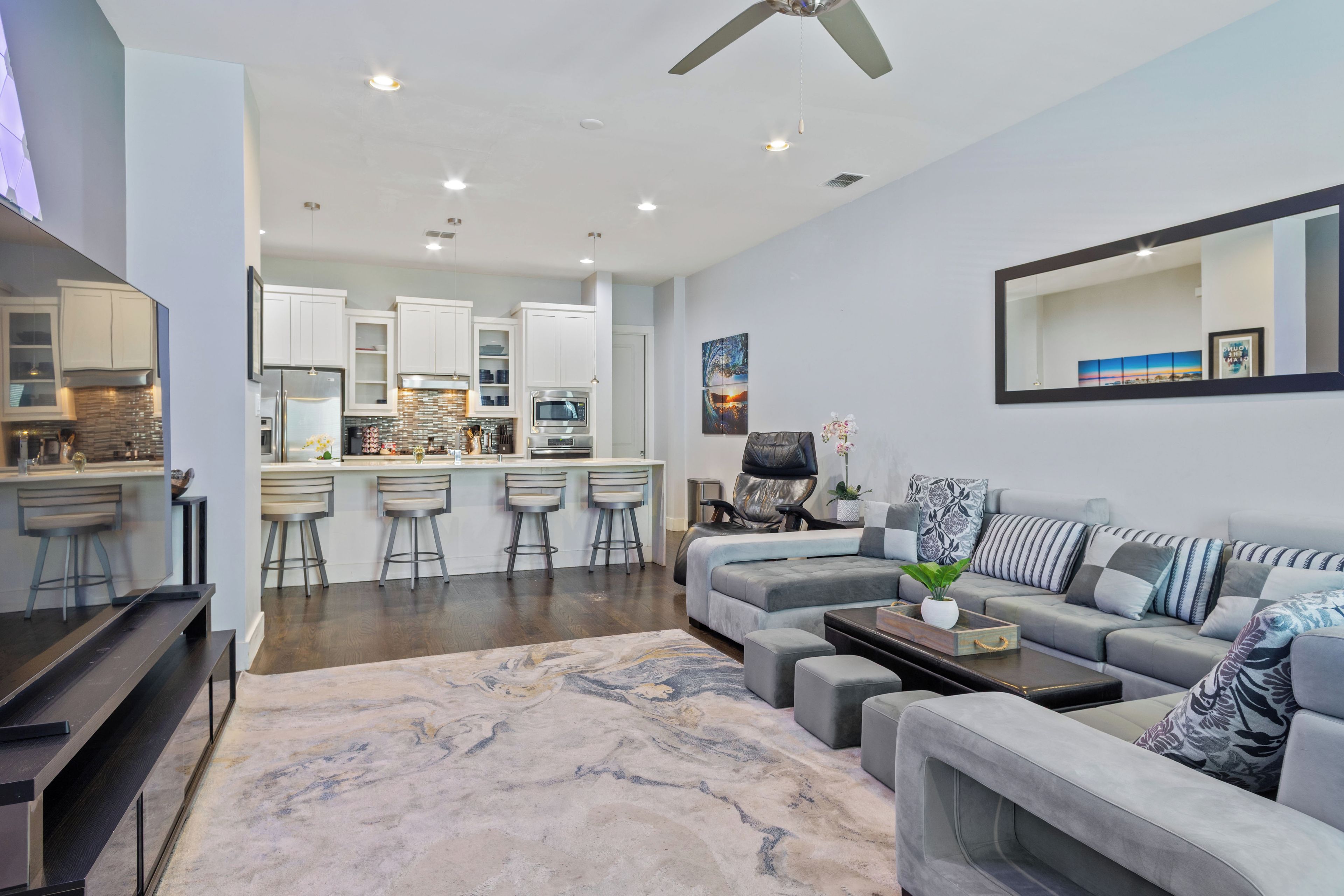 A modern living room with a grey sofa, a coffee table, and a large mirror.