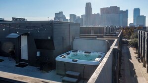 A rooftop with a hot tub, outdoor seating, and a city skyline in the background. - Modern 2 BR, 4 Story Smarthome with Rooftop Hot Tub, Game Room and Skyline Views (Dallas)