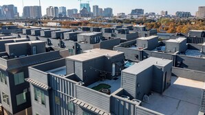 A modern urban hotel with multiple rooftop units, each featuring a small patio area. - Modern 2 BR, 4 Story Smarthome with Rooftop Hot Tub, Game Room and Skyline Views (Dallas)