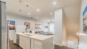 A modern kitchen with white cabinetry, a built-in dishwasher, and a central island. - Modern 2 BR, 4 Story Smarthome with Rooftop Hot Tub, Game Room and Skyline Views (Dallas)