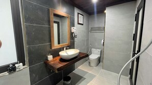 A modern bathroom with a wooden vanity, a large mirror, a toilet, and a shower area.