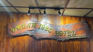 A wooden sign for Dream 1985 Hotel with contact information.