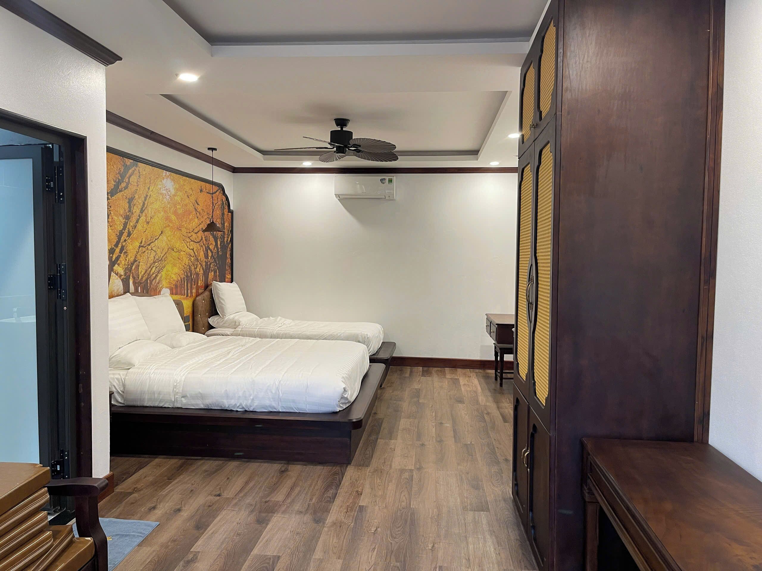 Un dormitorio con dos camas, ventilador de techo y piso de madera.