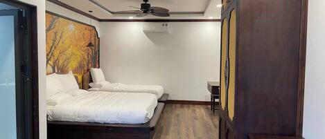 Un dormitorio con dos camas, ventilador de techo y piso de madera.