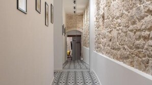 A hallway with a stone wall, tiled floor, and framed pictures on the wall. - Villa Casa Di Pietra (Sibenik)