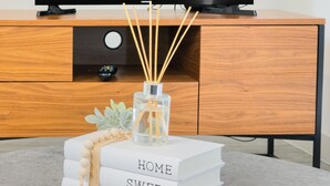 A television displaying the Netflix logo, a wooden cabinet, and a stack of books with the words "HOME SWEET HOME" on a table. - Salford - 2 Bed Apartment - Sleeps 4 - Wifi (Salford)