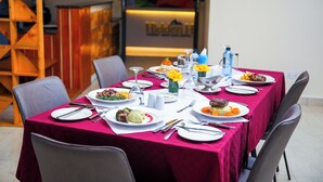 A dining table set with plates, cutlery, and various dishes, surrounded by chairs. - Hidden Hills Luxury Boutique Hotel (Nairobi)
