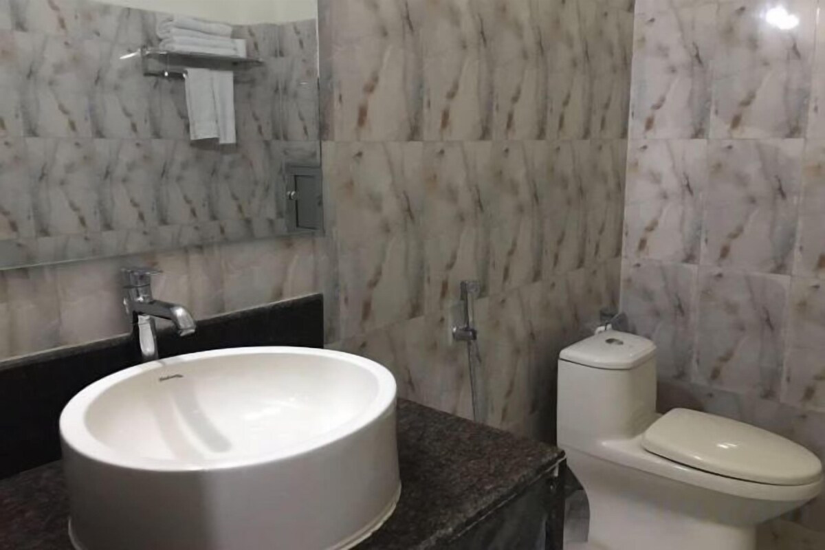 A bathroom with a marble sink, a toilet, and a mirror.