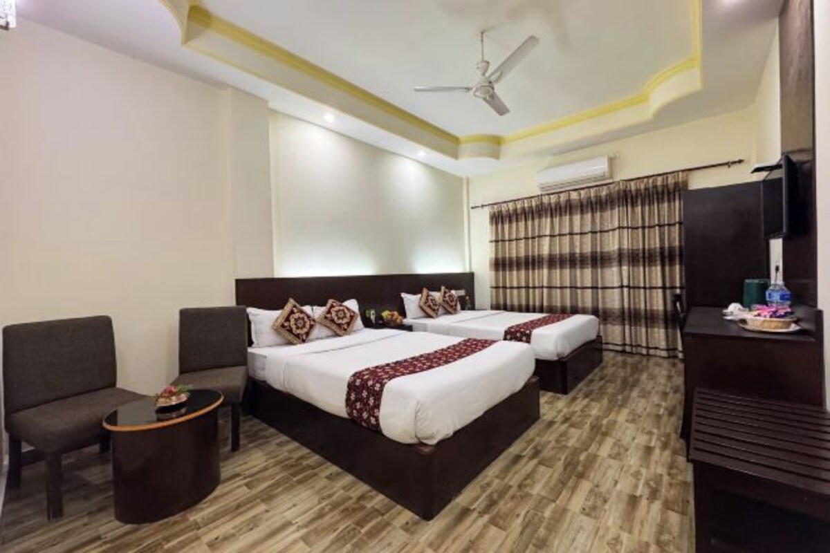 A hotel room with two beds, a ceiling fan, a TV, and a small table.