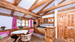 Una cocina rústica con vigas de madera, un comedor con mesa y sillas, y un mueble de madera grande.