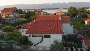 A residential area with houses featuring red-tiled roofs, surrounded by greenery and a body of water in the background. - Kata Peaceful Apartment (Nin)