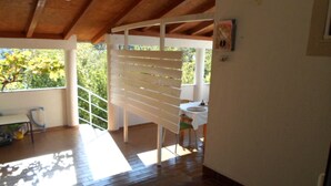 A covered patio area with a wooden ceiling, a white bench, and a table with chairs. - Kata Peaceful Apartment (Nin)