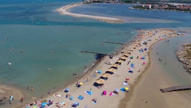 An aerial view of a beach with rows of beach umbrellas and people sunbathing. - Kata Peaceful Apartment (Nin)