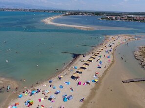 An aerial view of a beach with rows of beach umbrellas and people sunbathing. - Kata Peaceful Apartment (Nin)