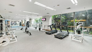 A modern gym with treadmills, weight machines, and a large window with a view of greenery. - Brassia by Kozystay - Thamrin (Jakarta)