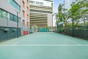 An indoor tennis court with a net in the center, surrounded by a fence and trees. - Brassia by Kozystay - Thamrin (Jakarta)