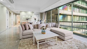 A modern living room with a sectional sofa, a coffee table, and a large window offering a view of the city. - Brassia by Kozystay - Thamrin (Jakarta)