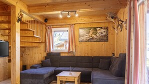 Ein Holzinterieur mit einem Ecksofa, einem kleinen Holztisch und einem Gemälde an der Wand.