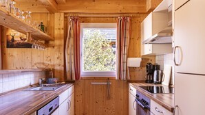 Eine kleine Küche mit Holzausstattung, einer Spüle, einem Herd und einem Fenster mit Vorhängen.