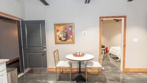 Ein Zimmer mit einem runden Tisch, zwei Stühlen, einem Bild an der Wand und einer Tür zu einem anderen Raum.