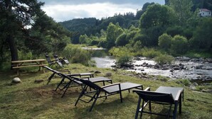Ein Sitzbereich im Freien am Flussufer mit Liegestühlen und einem Picknicktisch.
