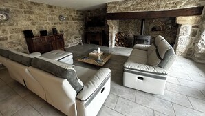 Ein gemütliches Wohnzimmer mit Steinwänden, einem Kamin, einer Couch und einem Couchtisch.